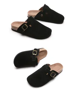 Detailed view of black suede clogs with adjustable buckles and cork-textured soles