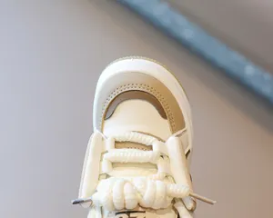 Primer plano de zapatillas altas beige para niños con cordones gruesos de moda