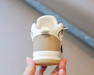 Detalle posterior de zapatillas deportivas altas para niños en tonos beige y blanco puro