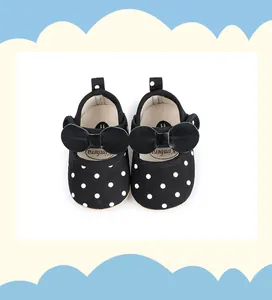 Gros plan de chaussures bébé noires à pois avec nœud et semelle souple antidérapante.