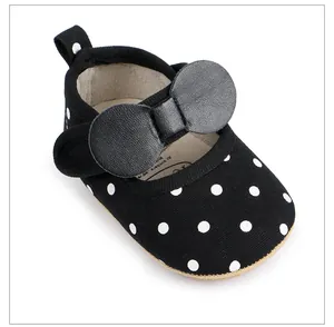 Détail macro d'une chaussure bébé noire à pois avec un grand nœud décoratif élégant