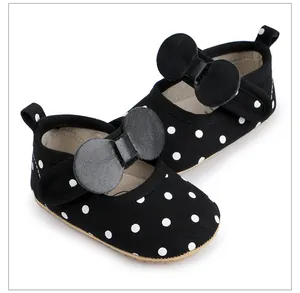 Détail de chaussures de marche pour bébé noires à pois avec un gros nœud