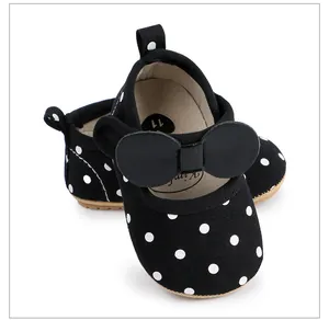Détail de chaussures bébé à pois noirs avec un joli nœud décoratif surdimensionné.