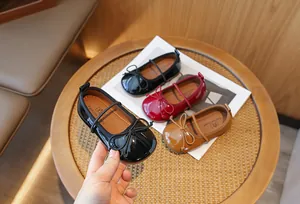 Glossy patent leather girls' ballet flats with elegant bow details and soft brown soles.