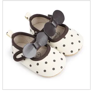 Vue détaillée de chaussures pour bébé fille à pois avec un grand nœud décoratif marron