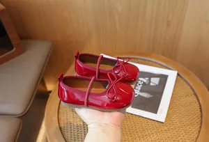 Detailed view of red patent leather Mary Jane shoes for girls with bow accents.