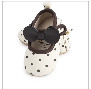 Vue détaillée de chaussures de marche pour bébé fille avec motif à pois et un nœud marron décoratif