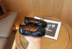 Macro view of glossy black patent leather girls' shoes with an elegant bow detail