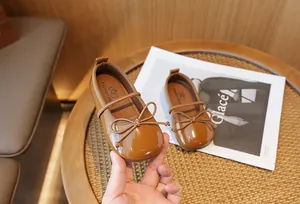 Elegant brown patent leather Mary Jane shoes for girls featuring a cute bow detail