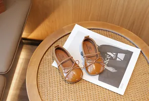 Detailed view of brown bow Mary Jane shoes for girls on a wooden table