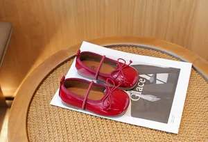 Red patent leather ballet flats for girls with elegant bow detail on a magazine