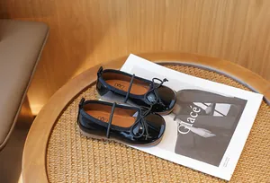 Close-up of black patent leather girl shoes with delicate bow detail on a lifestyle prop