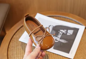 Close-up of a brown shiny leather girl's Mary Jane shoe featuring a cute bow detail