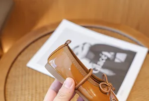 Detailed view of caramel brown patent leather Mary Jane shoes for girls with bow decor