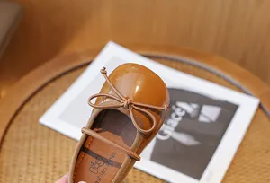 Close-up detail of brown patent leather girls' princess shoe with a delicate bow