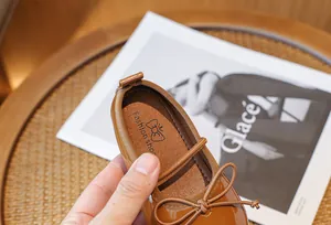 Close-up view of brown children's patent leather princess shoe featuring a bow detail