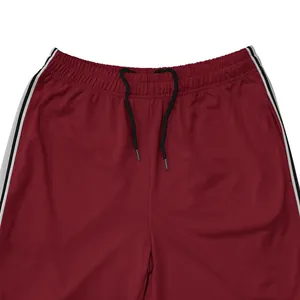 Detail van de bordeauxrode joggingbroek voor heren met trekkoord en zijstrepen.