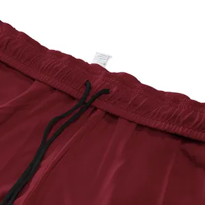Detailopname van heren burgundy joggingbroek met elastische taille en trekkoord.