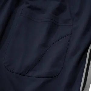 Detailweergave van de ademende mesh-stof en de stiksels van de achterzak van de donkerblauwe jogger.
