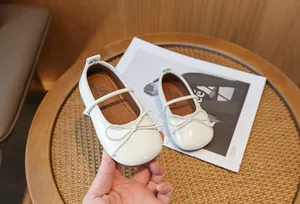 Close-up view of off-white children's princess shoes featuring a delicate bow detail