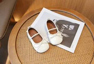 Elegant cream girls' Mary Jane shoes with delicate bow-knot detail on a woven background