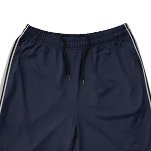 Detailopname van de marineblauwe joggingbroek met trekkoord en zijstrepen aan de kant.