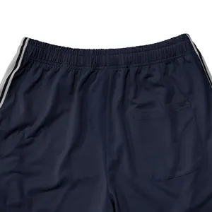 Detailweergave van een donkerblauwe sportbroek met elastische taille en zijstrepen.