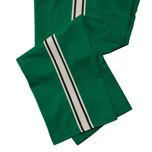 Detailopname van een groene heren joggingbroek met sportieve zwart-witte zijstrepen.