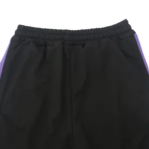 Detailopname van de elastische tailleband van een zwarte heren sportbroek met paarse strepen