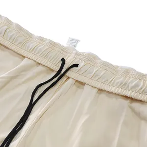 Detail van de tailleband van een crème heren joggingbroek met een zwart trekkoord design