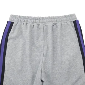 Detail van een grijze herensportbroek met elastische tailleband en zijstrepen.