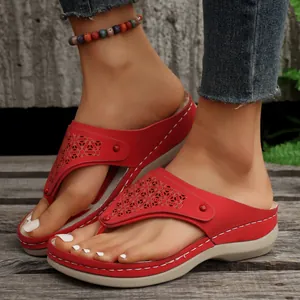 Vista dettagliata di infradito rosse con zeppa in stile etnico da donna su legno