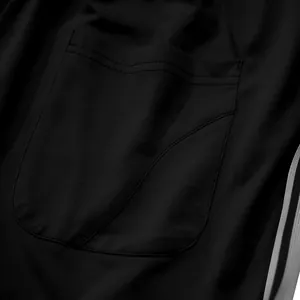 Detailopname van de zakstiksels op een zwarte ademende sportieve joggingbroek