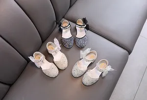 Detailansicht von drei glitzernden Prinzessinnenschuhen für Mädchen mit Perlenriemen und Schleifen