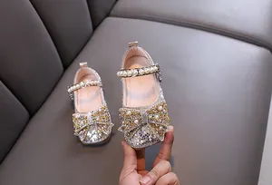 Detalle de zapatos de princesa para niñas con pedrería brillante, perlas y un lazo