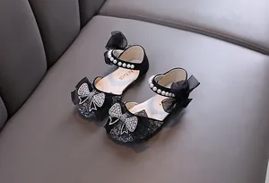 Detailed view of black girls' princess shoes featuring rhinestone bow and pearls