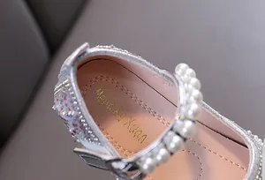 Vista macro de zapato de princesa plateado con correa de perlas y purpurina