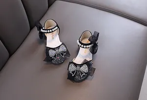 Close-up of girl's black princess shoes with rhinestone bows and pearl straps