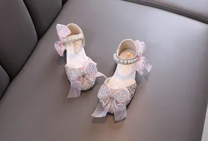 Detailed view of pink princess shoes with sparkling rhinestones, pearls, and mesh bows
