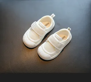 Close-up of white children's indoor canvas shoes with breathable mesh and velcro straps.