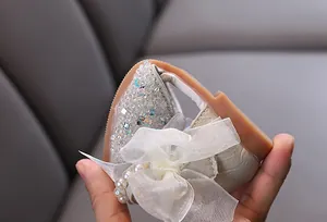 Close-up of flexible sole on sparkly girls' princess shoes with bow and pearl detail