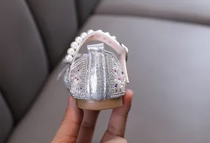 Close-up of silver girl's princess shoe heel with rhinestones and pearl strap