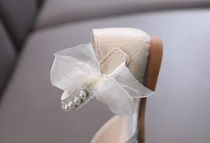 Detailed view of the elegant mesh bow and pearl strap on girls' princess shoes