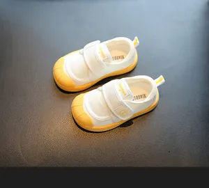 Detailed view of white and yellow toddler indoor shoes with mesh fabric and velcro straps