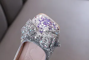 Close-up detail of silver glitter bow and sparkling sequins on girl's princess shoe
