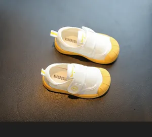 Detail of white baby indoor shoes with soft yellow rubber soles and mesh fabric.
