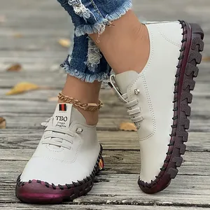 Detailed view of cream leather flats with maroon hand-stitched rubber soles
