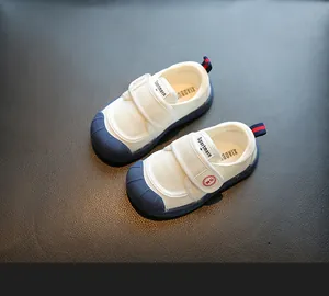 Detailed view of kids white indoor canvas shoes with navy rubber toe and velcro strap