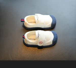 Top-down detail view of white toddler canvas shoes with navy blue protective toe caps