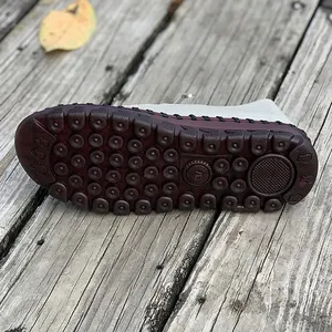 Detailed view of the textured non-slip tendon sole on white flat casual mother shoes